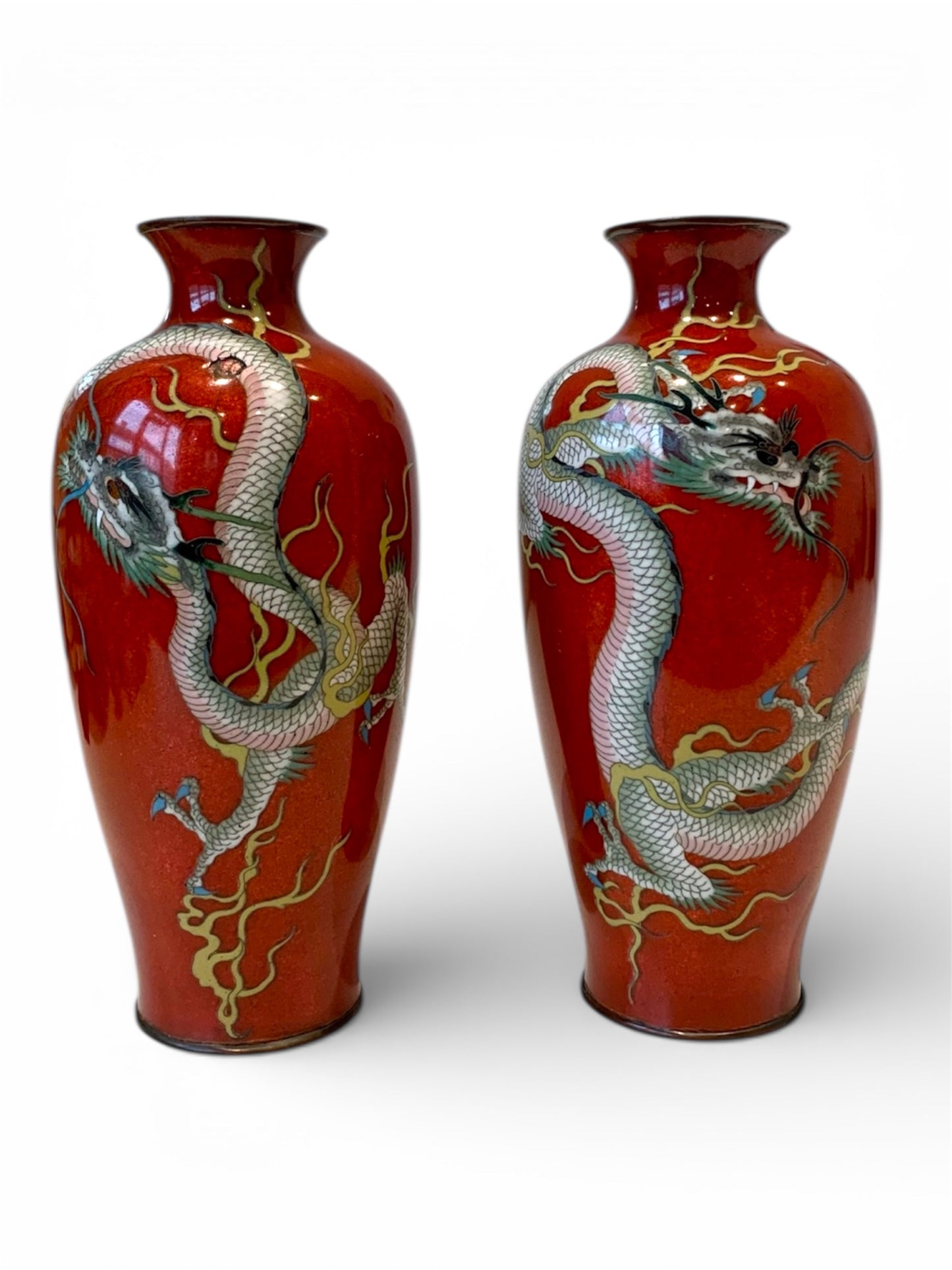 A fine pair of Japanese cloisonné enamel vases decorated with dragons on a rich red ground, Meiji period
